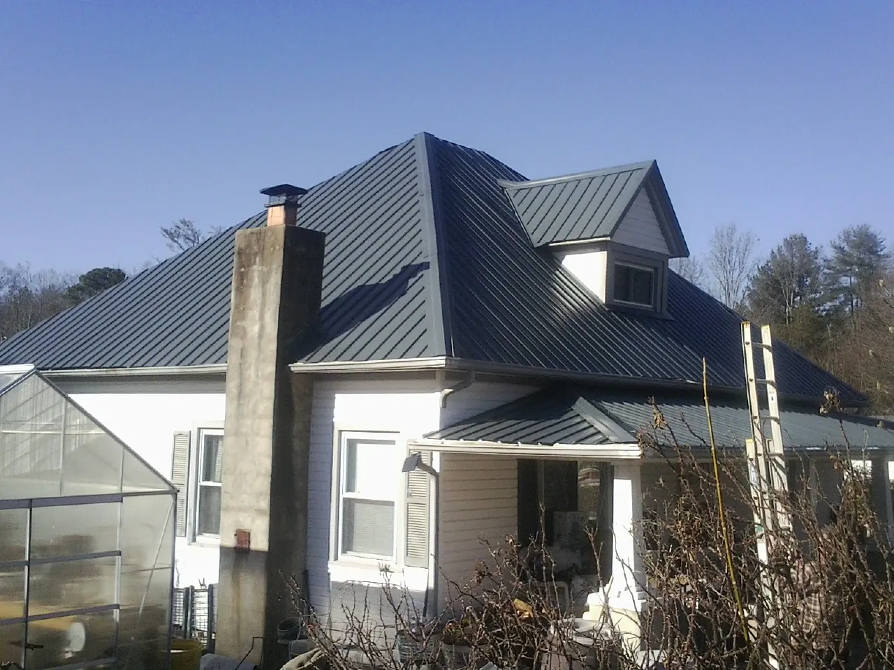 Dark blue standing seam metal roof on a white farmhouse with dormer — Slate & Tile Roof Repair by Roofing Brothers in New Windsor
