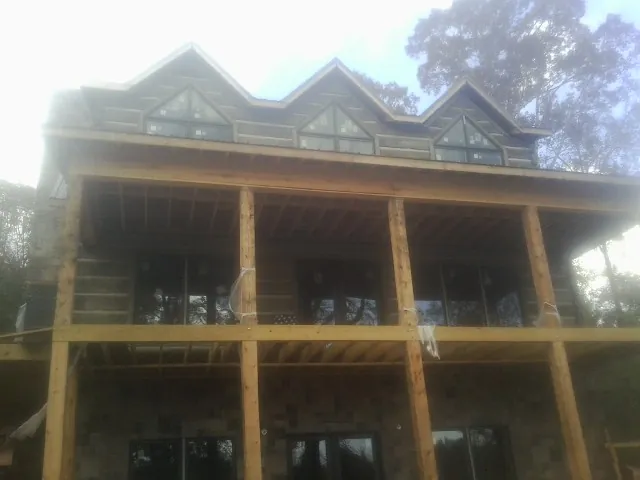 Dormers and porch framing on a large log home under construction — Roof Coating work by our crew in New Windsor